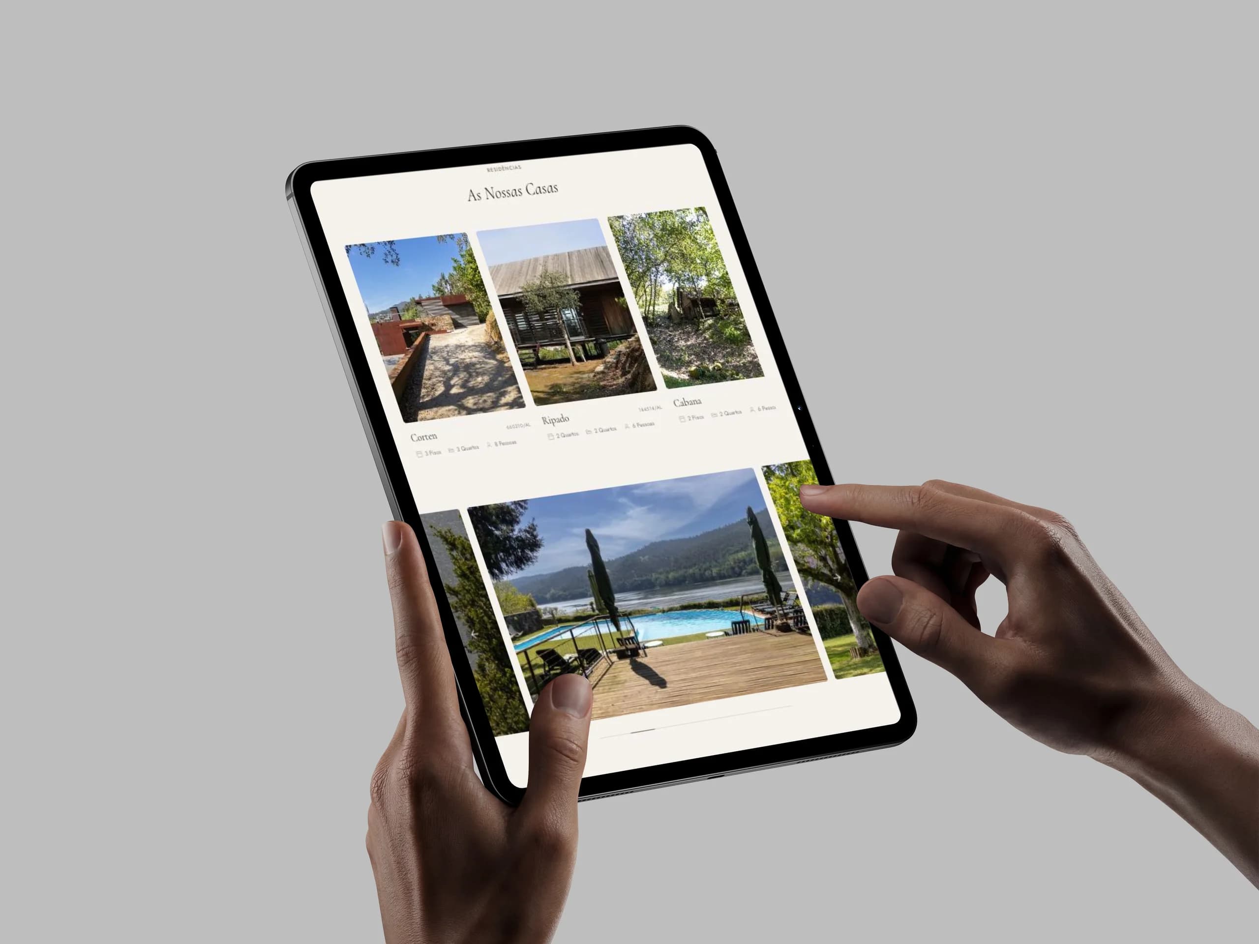 A página "As Nossas Casas" em tablet, com a grelha das casas (Corten, Ripado, Cabana) e a piscina com vista sobre o rio.